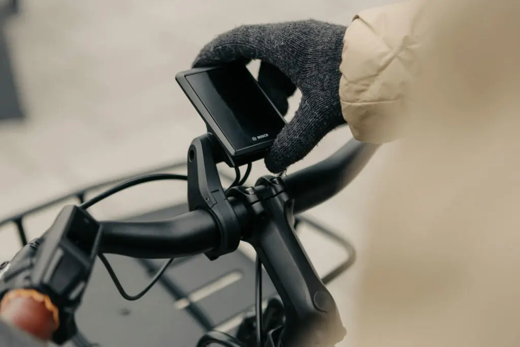 Kesztyűs kéz a Bosch Kiox kijelzőn egy e-bike kormányán